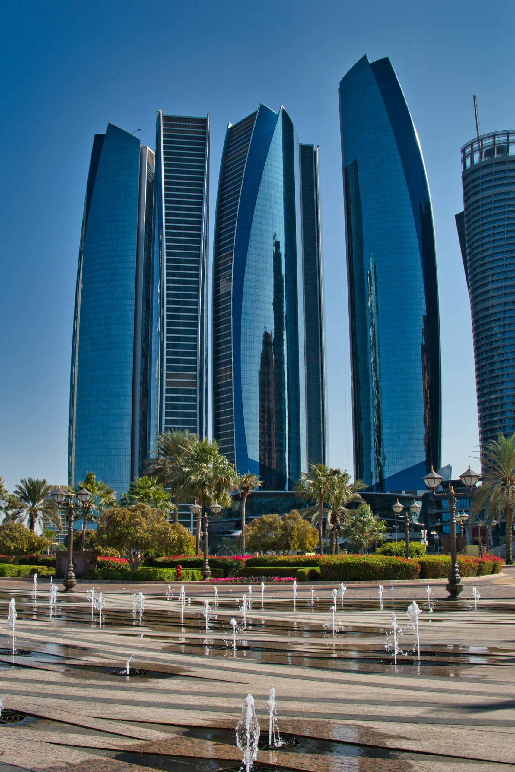 Etihad Towers above palm trees and fountains in Abu Dhabi