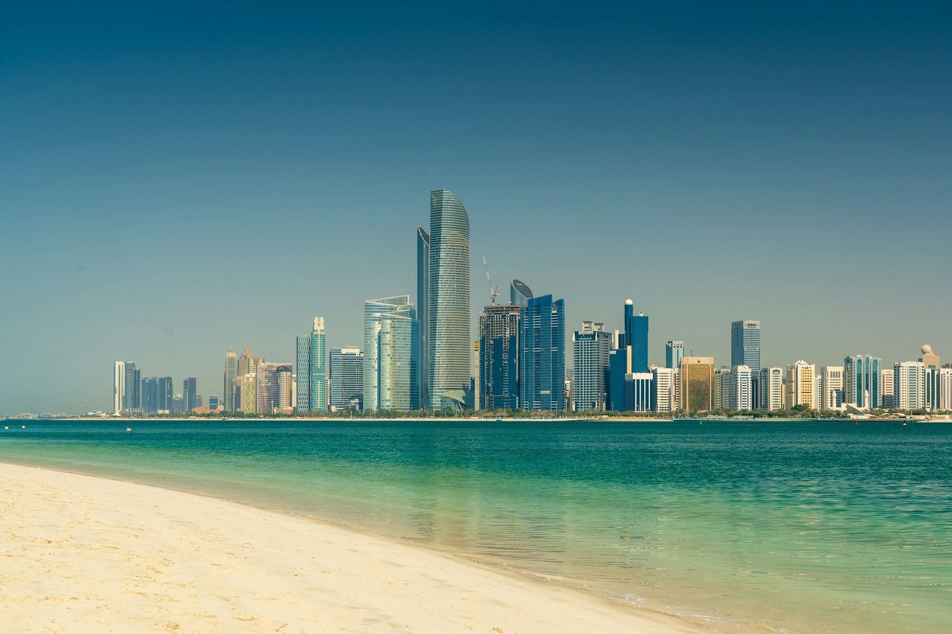Abu Dhabi waterfront skyline and modern towers viewed across turquoise water in daylight